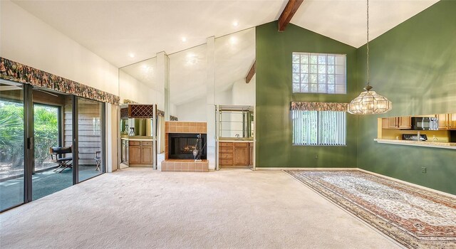 unfurnished living room featuring high vaulted ceiling, a healthy amount of sunlight, an inviting chandelier, and carpet