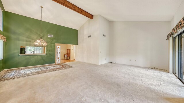 unfurnished living room with an inviting chandelier, beamed ceiling, high vaulted ceiling, and carpet floors