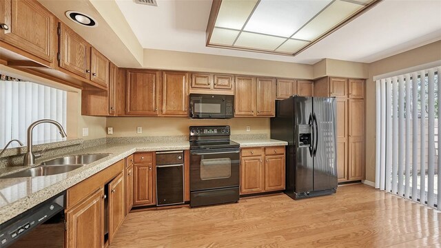 kitchen featuring light wood-type flooring, black appliances, plenty of natural light, and sink