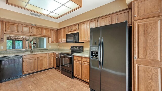 kitchen featuring black appliances, sink, and light hardwood / wood-style floors