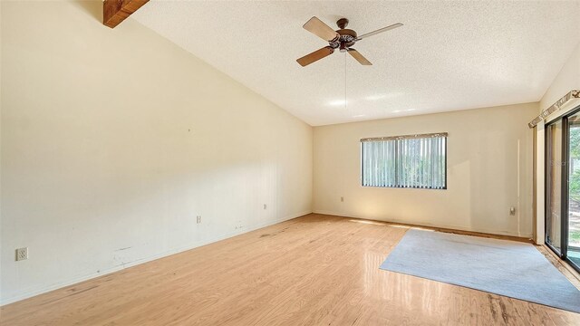 unfurnished room featuring a wealth of natural light, light hardwood / wood-style flooring, ceiling fan, and lofted ceiling with beams