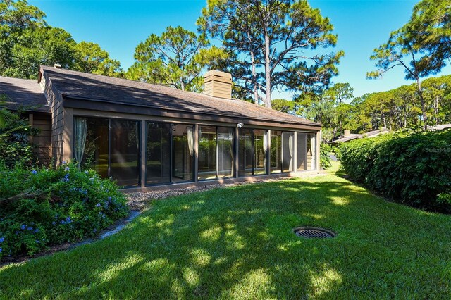 rear view of house with a sunroom and a lawn