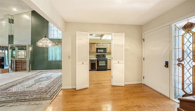 foyer featuring an inviting chandelier, a textured ceiling, and light hardwood / wood-style flooring