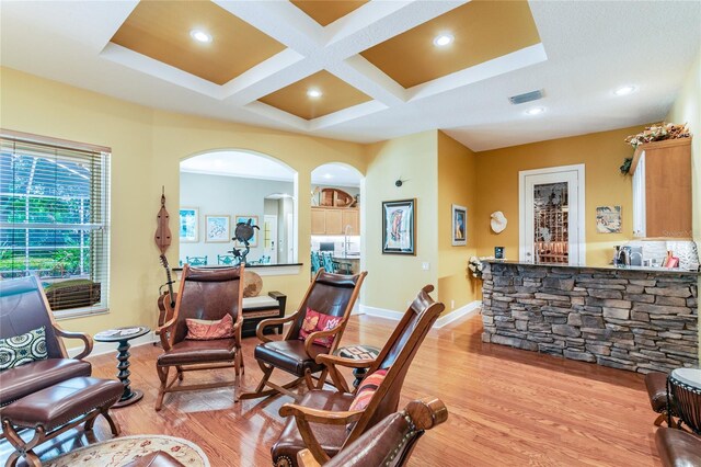 living room with coffered ceiling, light hardwood / wood-style floors, and beamed ceiling