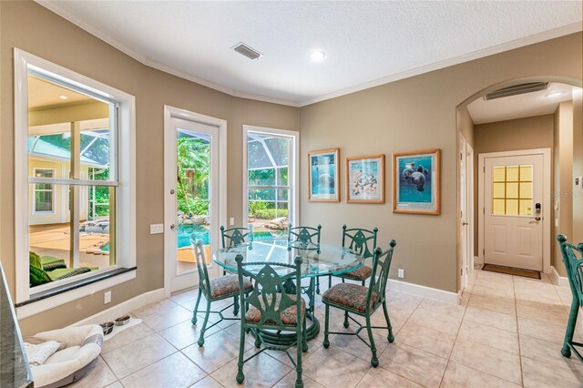 dining room with a textured ceiling, ornamental molding, and light tile floors