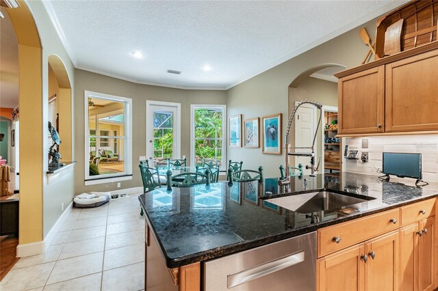 kitchen featuring sink, tasteful backsplash, light tile floors, and a textured ceiling