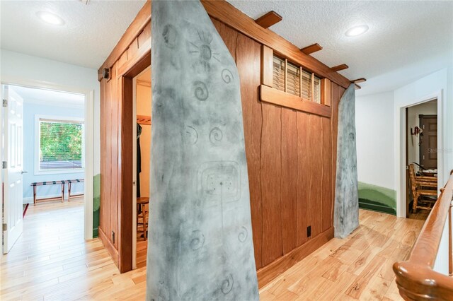 corridor with a textured ceiling and light hardwood / wood-style floors