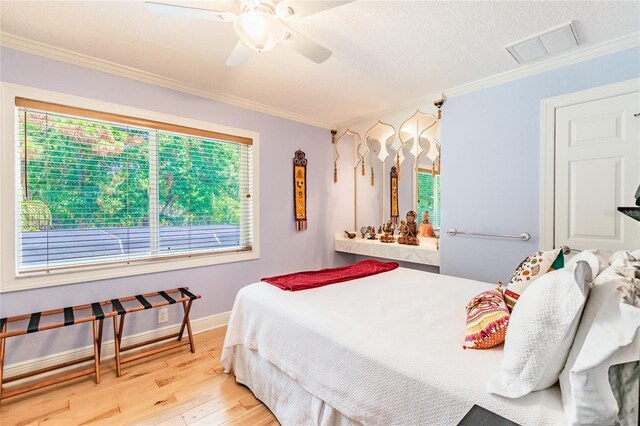 bedroom with crown molding, light hardwood / wood-style floors, ceiling fan, and multiple windows