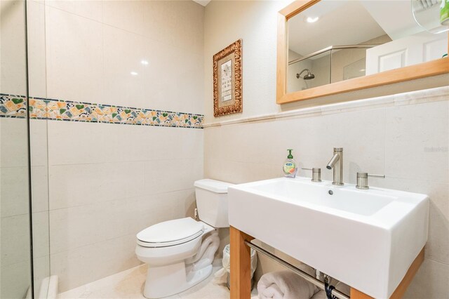 bathroom featuring a tile shower, toilet, and tile walls