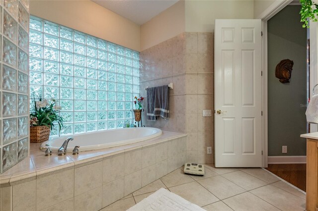 bathroom featuring tile floors, a wealth of natural light, tiled bath, and vanity