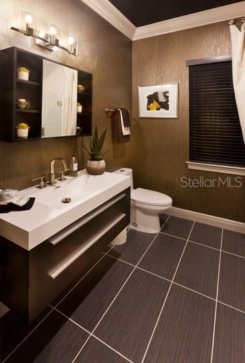 bathroom with tile flooring, crown molding, toilet, and vanity