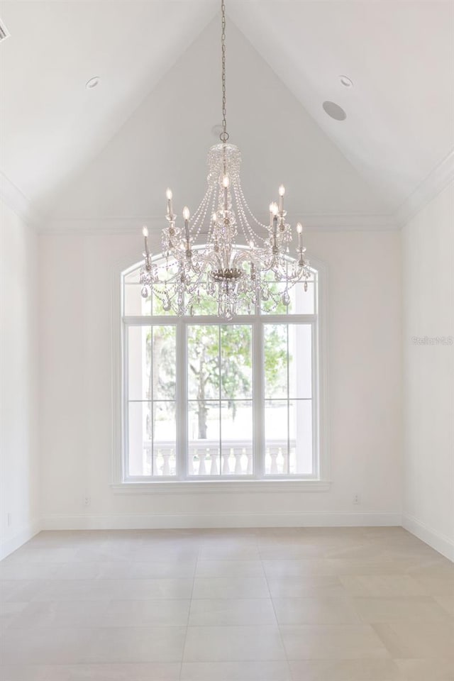 tiled empty room with ornamental molding, lofted ceiling, a wealth of natural light, and an inviting chandelier