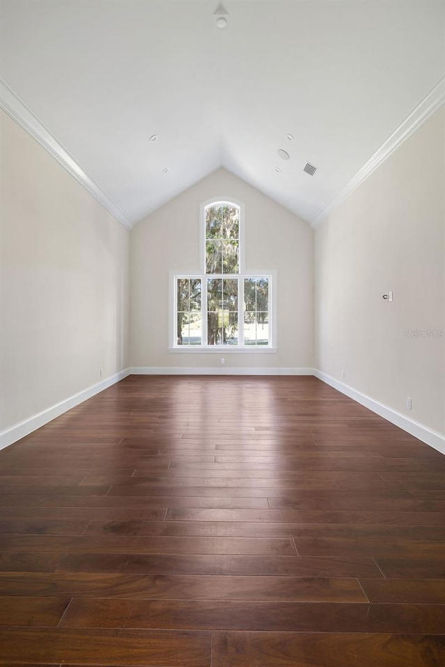 spare room with vaulted ceiling, crown molding, and dark hardwood / wood-style flooring