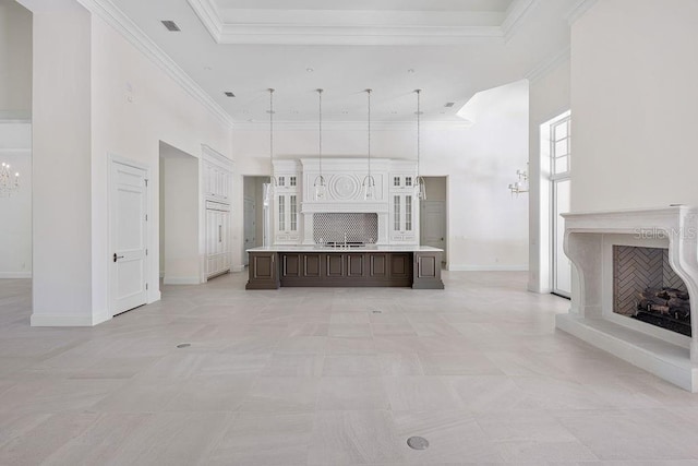 unfurnished living room featuring ornamental molding, sink, light tile floors, and a towering ceiling