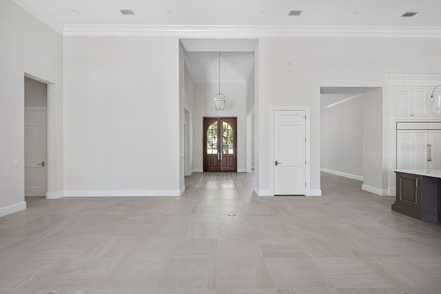 spare room featuring crown molding, light tile floors, and a high ceiling