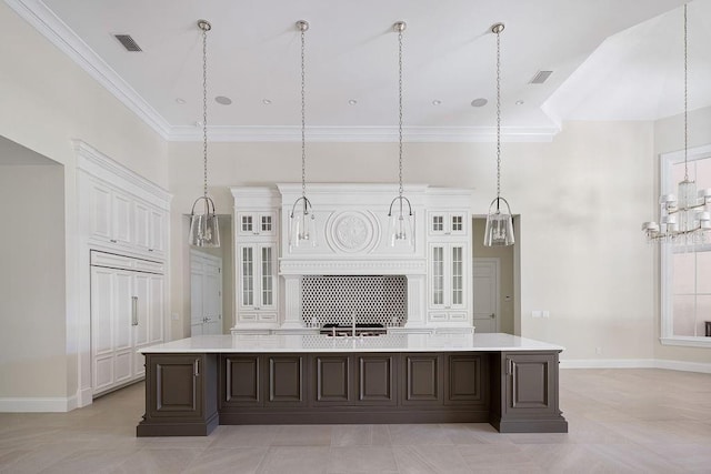 kitchen featuring a large island with sink, decorative light fixtures, and white cabinets