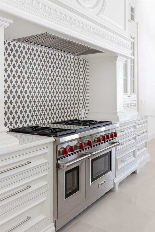 kitchen featuring white cabinets, range with two ovens, and backsplash