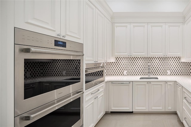 kitchen featuring backsplash, double oven, white cabinets, and sink