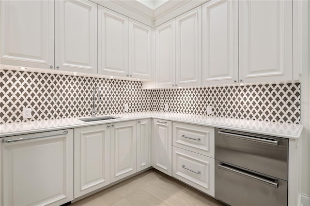 kitchen with tasteful backsplash, white cabinetry, and sink