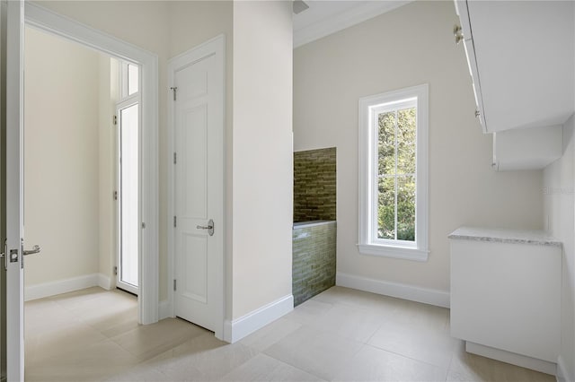 interior space featuring ornamental molding, a healthy amount of sunlight, and light tile floors