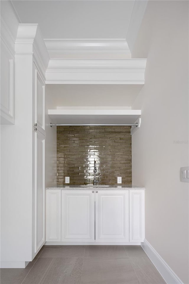 bar featuring tasteful backsplash, tile flooring, and sink