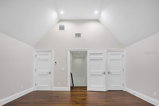 unfurnished bedroom with high vaulted ceiling and dark wood-type flooring