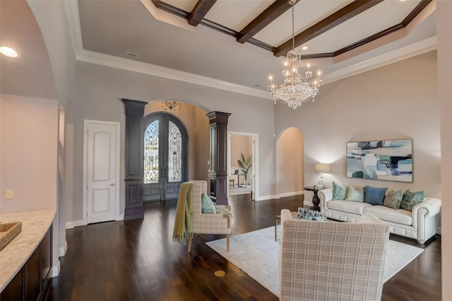 living room featuring dark wood-type flooring, beamed ceiling, ornate columns, ornamental molding, and a chandelier