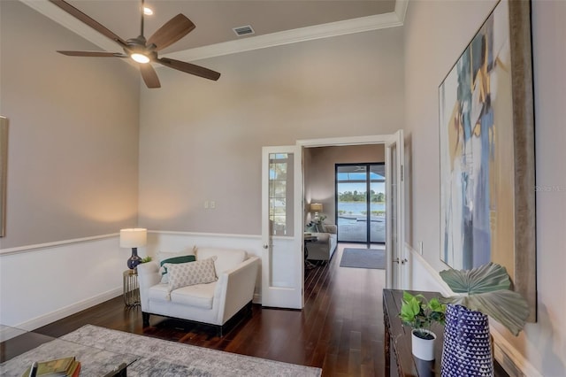 sitting room with ceiling fan, dark hardwood / wood-style floors, ornamental molding, and a towering ceiling