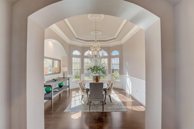 dining room featuring an inviting chandelier, a raised ceiling, crown molding, and hardwood / wood-style floors