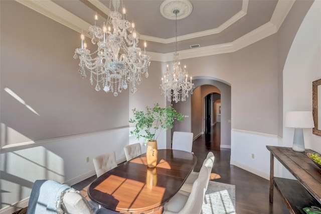 dining area featuring a notable chandelier, a tray ceiling, ornamental molding, and dark hardwood / wood-style flooring