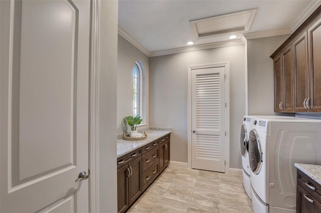 clothes washing area with cabinets, crown molding, and washing machine and clothes dryer