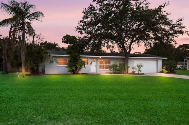 ranch-style home featuring a garage and a lawn