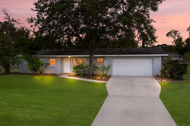 ranch-style home featuring a garage and a lawn