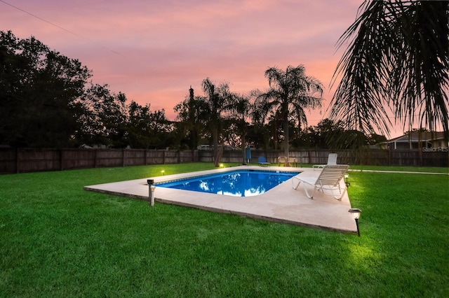 pool at dusk featuring a patio and a yard