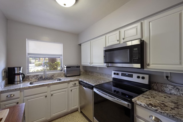 kitchen with white cabinets, sink, stainless steel appliances, and light stone counters