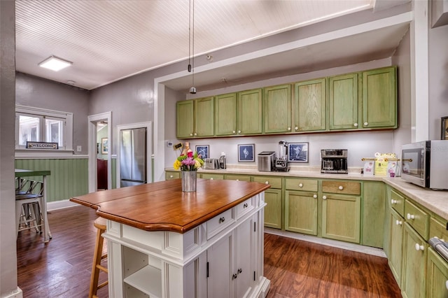 kitchen featuring dark hardwood / wood-style flooring, wooden walls, and green cabinets