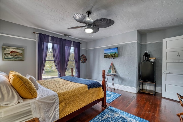 bedroom featuring ceiling fan, dark hardwood / wood-style flooring, and a textured ceiling