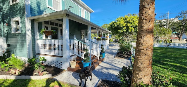 view of side of property with covered porch and a lawn