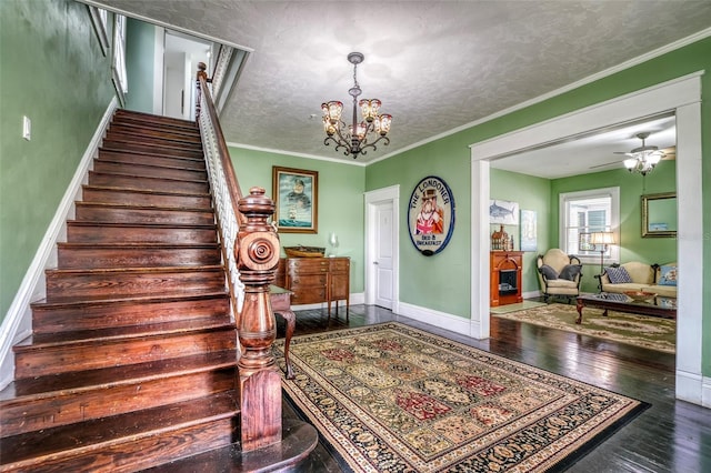 stairs featuring a textured ceiling, ceiling fan with notable chandelier, ornamental molding, and wood-type flooring