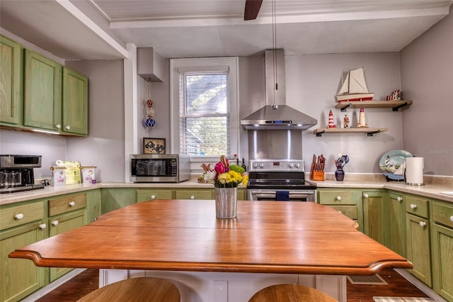 kitchen featuring breakfast area, stainless steel appliances, green cabinets, and wall chimney range hood