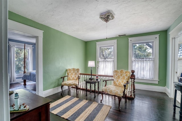 sitting room with dark wood-type flooring and a textured ceiling