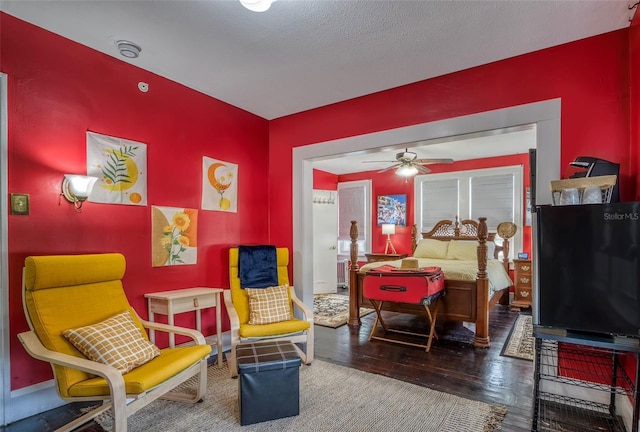 sitting room with wood-type flooring, a textured ceiling, and ceiling fan