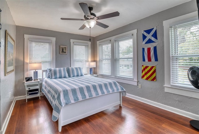 bedroom featuring multiple windows, ceiling fan, and dark hardwood / wood-style flooring