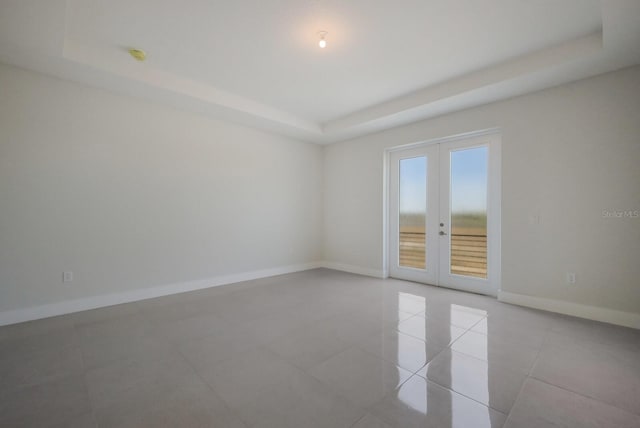 spare room featuring light tile patterned floors, a raised ceiling, and french doors