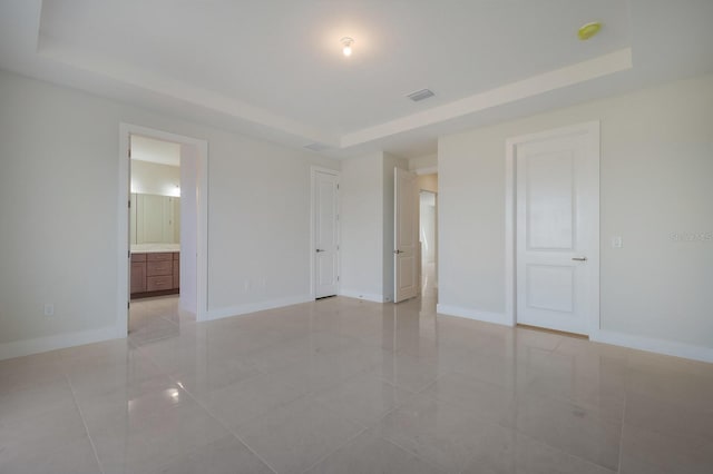 spare room with a raised ceiling and light tile patterned floors