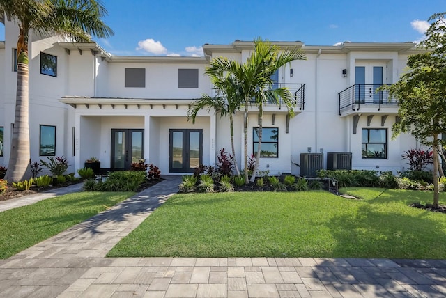 view of front of house with stucco siding, cooling unit, french doors, and a front yard