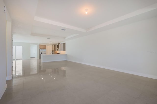 unfurnished living room featuring baseboards, visible vents, and a raised ceiling