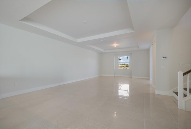 spare room featuring a tray ceiling and light tile patterned flooring