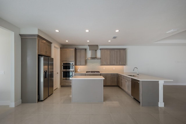 kitchen with visible vents, a peninsula, wall chimney exhaust hood, appliances with stainless steel finishes, and a sink