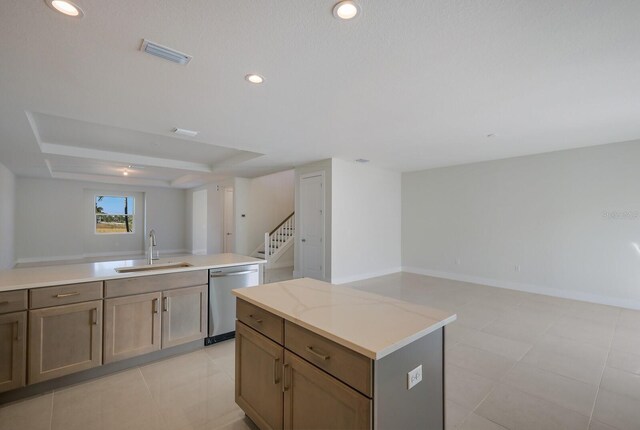 kitchen featuring a kitchen island, light stone countertops, light tile patterned floors, stainless steel dishwasher, and sink